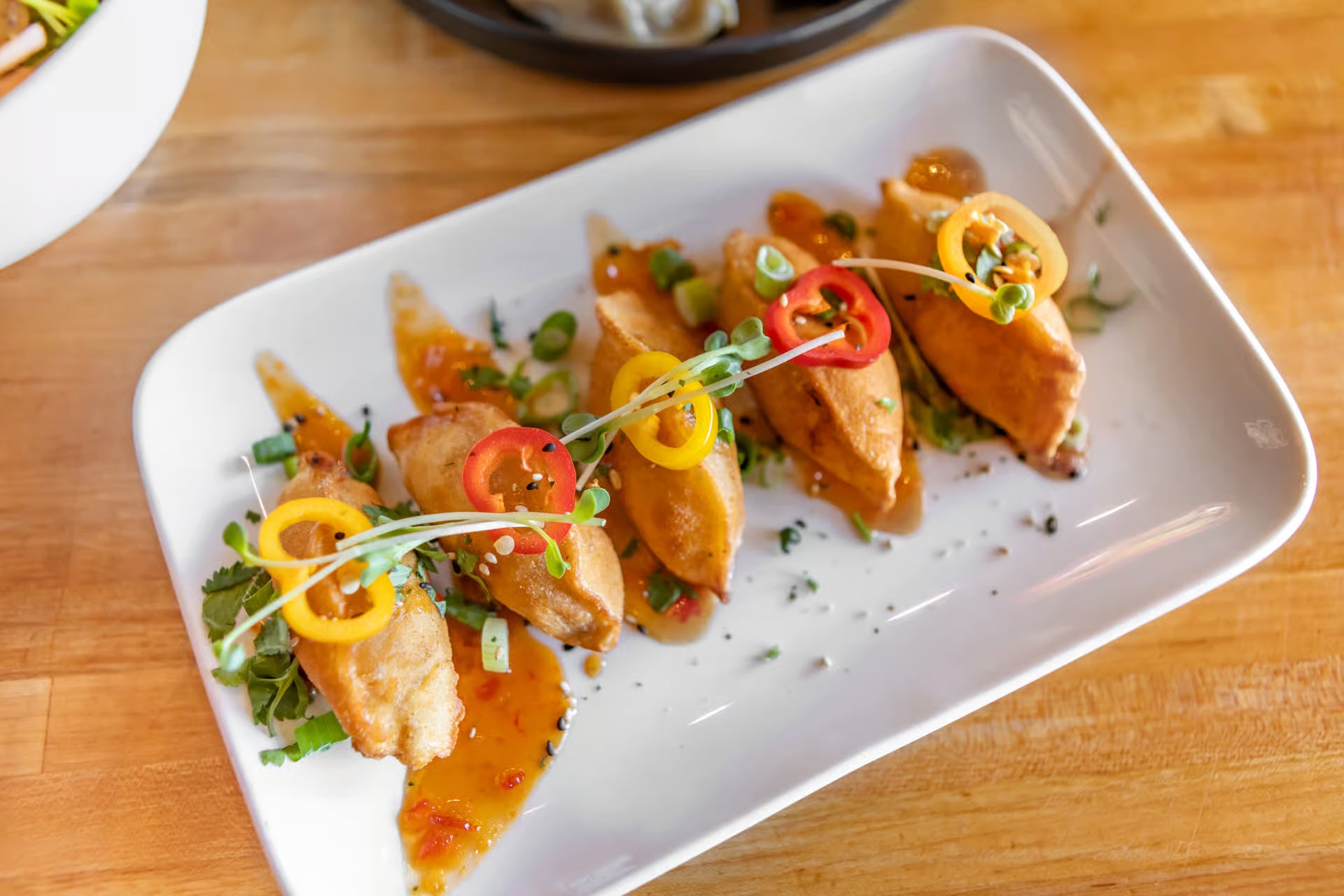 Plated dish dumplings with garnishes on a wooden table